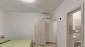 Ein Schlafzimmer mit Bett, Kleiderschrank und einem Badezimmer mit Waschbecken und Toilette.