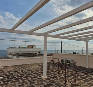 Eine Dachterrasse mit Meerblick, weißen Geländern und Satellitenschüsseln.