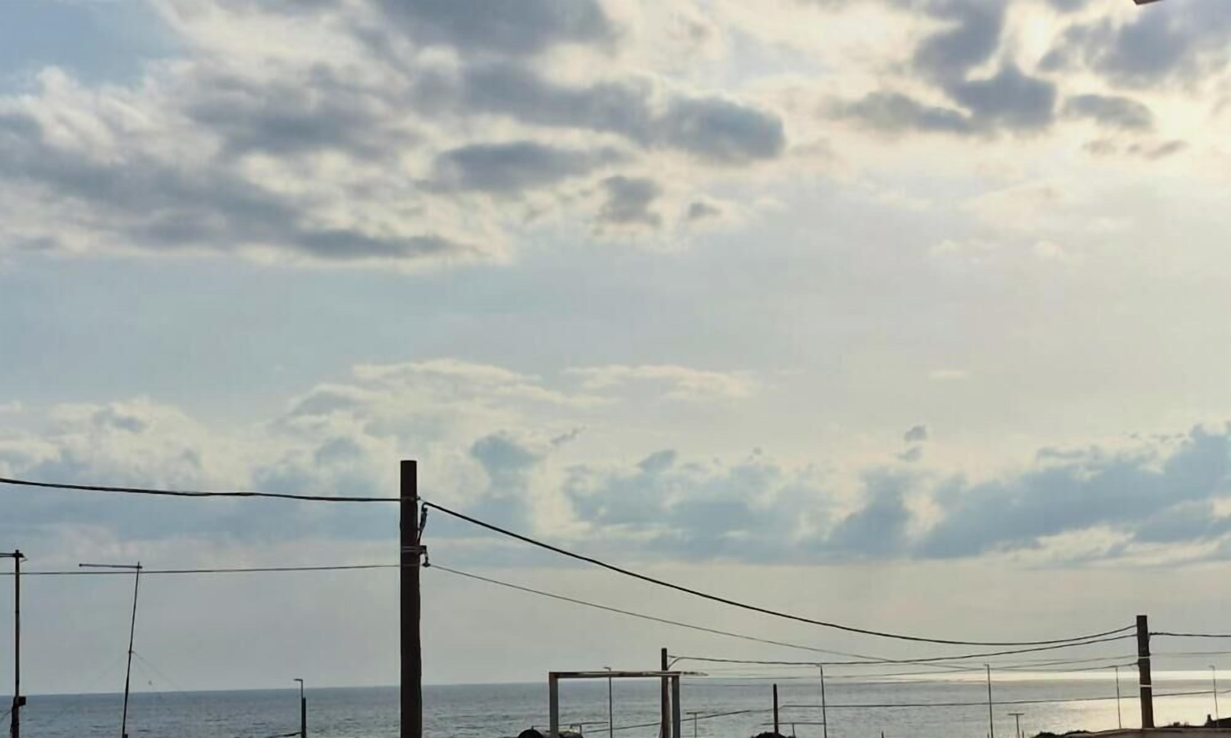 Uitzicht op de kust met elektriciteitskabels en een heldere lucht.