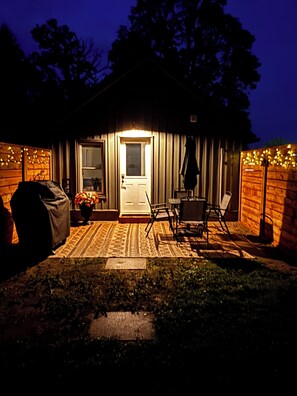 A wooden cabin with a porch, a grill, and string lights. - Rural Retreat. Private yard, fire pit. 3-30 mins to attractions & conveniences (Bothwell)