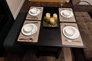 A dining table set with four white plates, cutlery, and candles. - Rural Retreat. Private yard, fire pit. 3-30 mins to attractions & conveniences (Bothwell)
