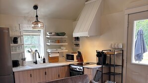 A modern kitchen with a built-in oven, microwave, and sink. There is a sofa and a small table with candles. - Rural Retreat. Private yard, fire pit. 3-30 mins to attractions & conveniences (Bothwell)