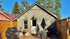 A small wooden shed with a door, a covered grill, and outdoor seating. - Rural Retreat. Private yard, fire pit. 3-30 mins to attractions & conveniences (Bothwell)