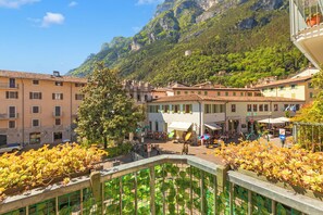 A town square with buildings, a tree, and a mountain backdrop. - Riva Dante Apartment - 4, Riva del Garda, Italy (Riva del Garda)