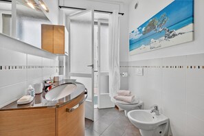 A modern bathroom with a wooden vanity, a sink, a toilet, and a bidet. - Riva Dante Apartment - 4, Riva del Garda, Italy (Riva del Garda)