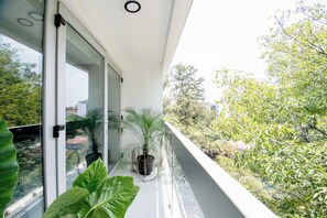 A balcony with a glass door, a potted plant, and a view of trees and buildings. - Massive rooftop terrace steps from everything (Mexico City)