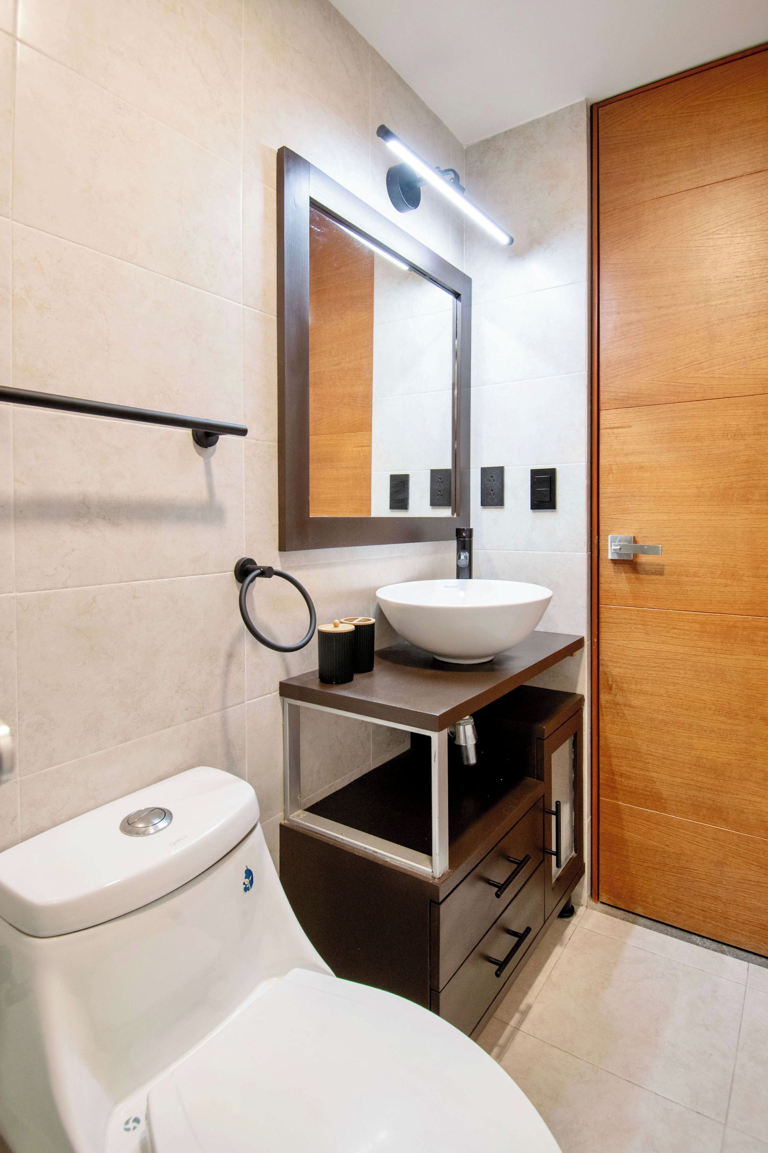Ein modernes Badezimmer mit Toilette, Waschbecken und Spiegel.