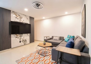 A modern living room with a sectional sofa, a coffee table, and a flat-screen TV mounted on the wall. - Massive rooftop terrace steps from everything (Mexico City)