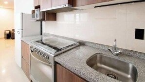 A modern kitchen with a stainless steel stove, microwave, and sink. - Massive rooftop terrace steps from everything (Mexico City)