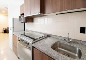Eine moderne Küche mit Edelstahlkochfeld, Mikrowelle und Spüle.
