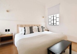 Une chambre à coucher avec un lit, une table de chevet, une lampe et une fenêtre donnant sur un beau paysage.