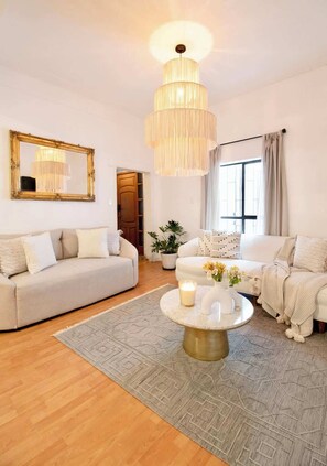 Un salon avec un lustre, deux canapés, une table basse et un miroir au mur.