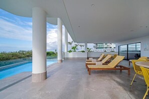 Ein moderner Außenbereich mit Liegebereich, Pool und Meerblick.