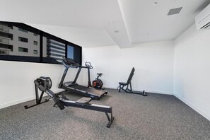 Ein Fitnessraum mit Laufbändern, einem Ergometer und einer Bank.