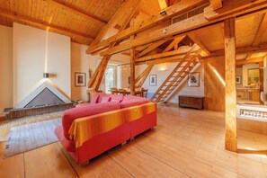 A spacious room with wooden beams, a red sofa, a fireplace, and a staircase. - Bel'Alp 24 Historical Residence Near Ski Lifts at Le Tour in Chamonix, Le Tour (Argentière), France (Le Tour (Argentière))