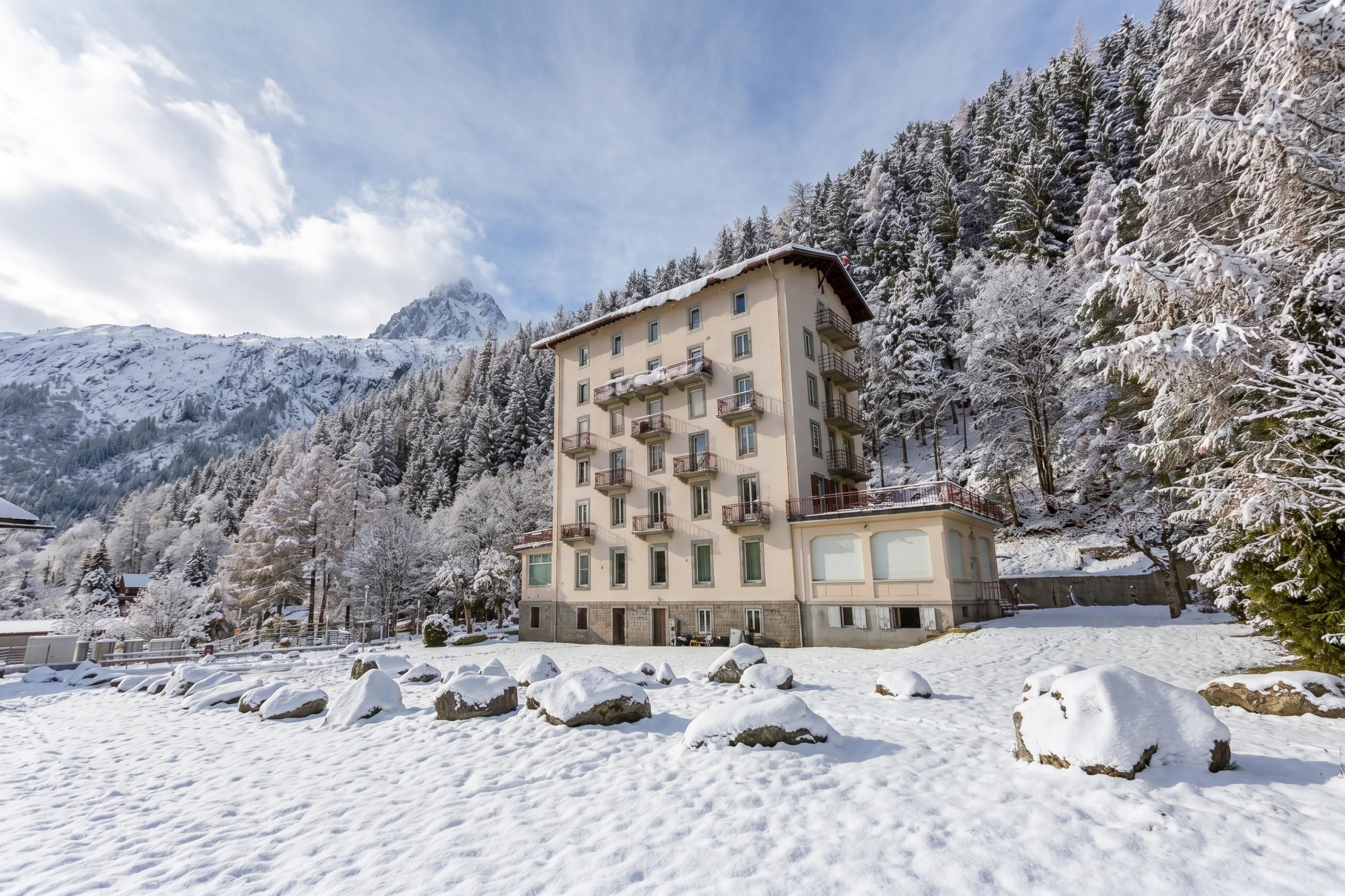 Un hôtel à plusieurs étages, doté de balcons, situé dans une région montagneuse enneigée.