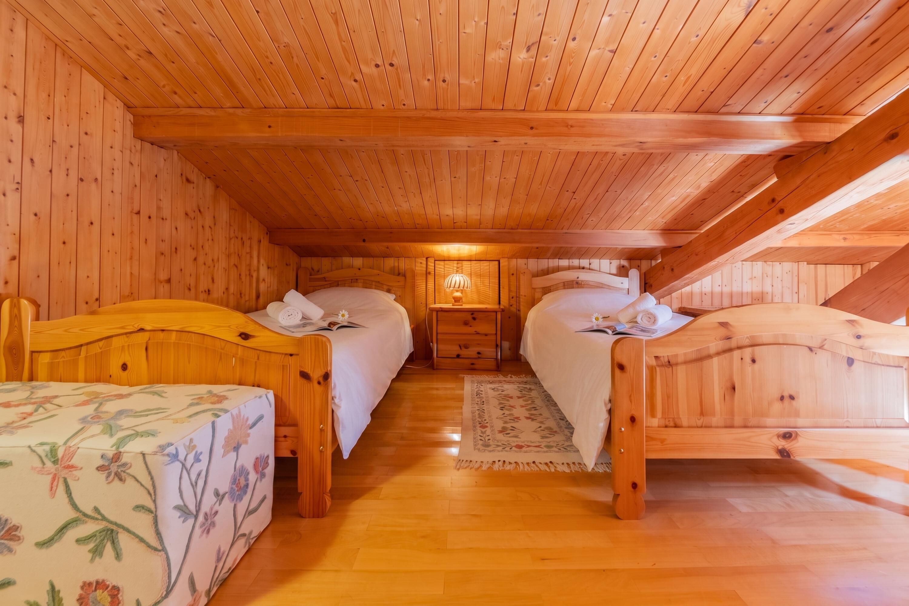 A cozy wooden cabin room with two beds, a nightstand, and a small rug.