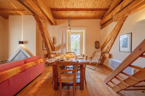A wooden interior with a dining table, chairs, a red sofa, and a window with a view of trees. - Bel'Alp 24 Historical Residence Near Ski Lifts at Le Tour in Chamonix, Le Tour (Argentière), France (Le Tour (Argentière))