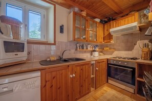 A kitchen with wooden cabinets, a Bosch dishwasher, a stove, and a window. - Bel'Alp 24 Historical Residence Near Ski Lifts at Le Tour in Chamonix, Le Tour (Argentière), France (Le Tour (Argentière))