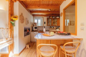A kitchen with wooden cabinets, a central island with chairs, and a window. - Bel'Alp 24 Historical Residence Near Ski Lifts at Le Tour in Chamonix, Le Tour (Argentière), France (Le Tour (Argentière))