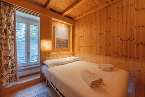 A wooden-paneled room with a bed, a window with curtains, and a wall-mounted shelf with items. - Bel'Alp 24 Historical Residence Near Ski Lifts at Le Tour in Chamonix, Le Tour (Argentière), France (Le Tour (Argentière))