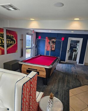 Ein Billardtisch in einem Raum mit blauer Wand, einer Tür zum Fitnessbereich und einem Poster an der Wand.