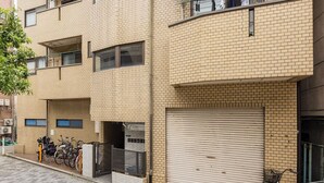 A multi-story building with a brick facade, balconies with clothes hanging, and bicycles parked outside. - Logement Tengachaya (Osaka, Nishinari ward, Tengachaya)