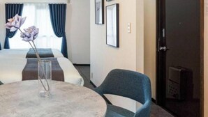 A hotel room with a bed, a round table with a vase, and a chair. - Logement Tengachaya (Osaka, Nishinari ward, Tengachaya)
