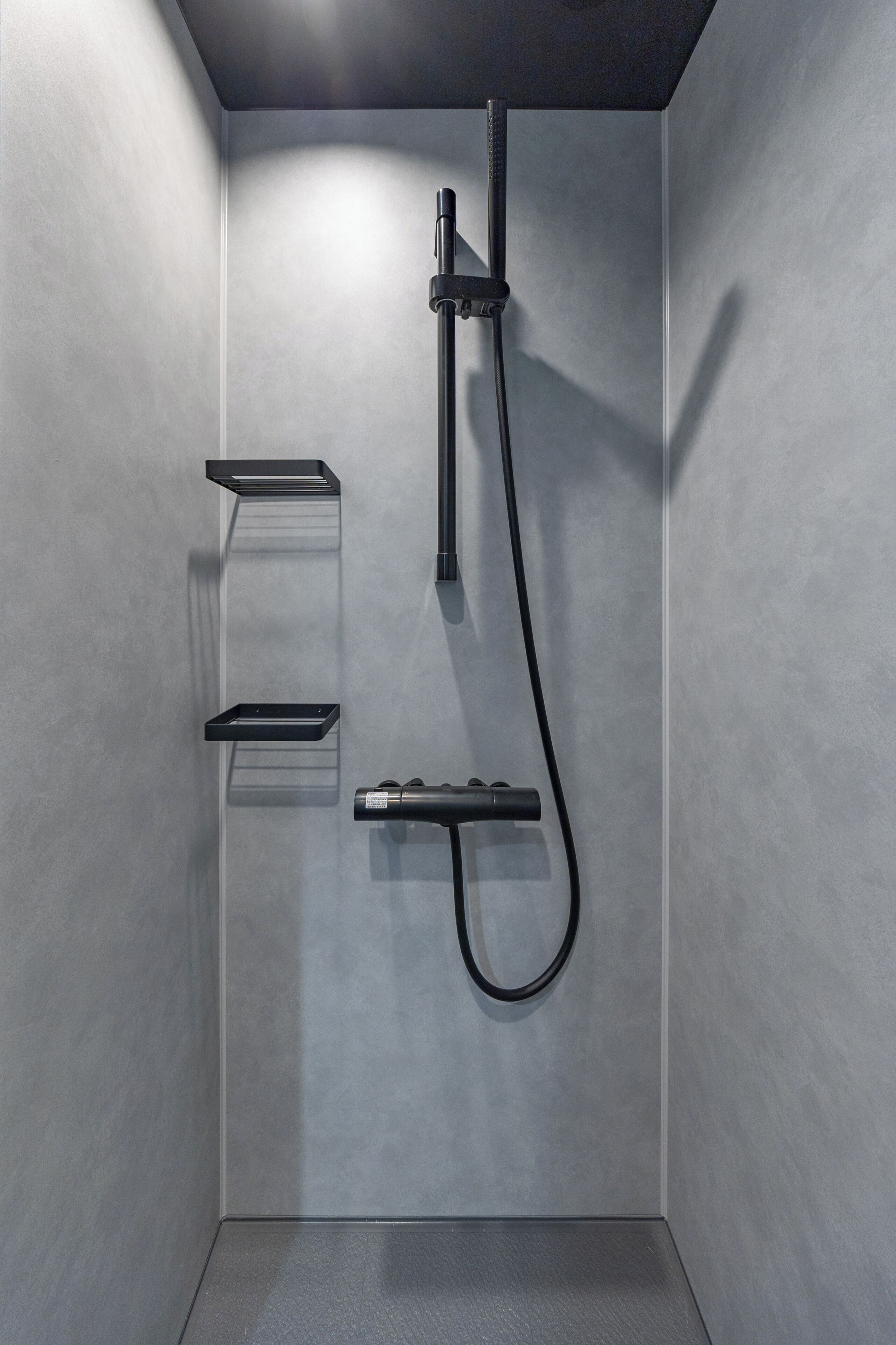 A modern shower with a handheld showerhead and a wall-mounted faucet.