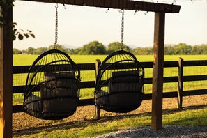 Una pergola in legno con due sedili a dondolo neri sospesi da catene.