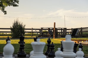 Een schaakspel buiten, met een houten hek en stoelen op de achtergrond.