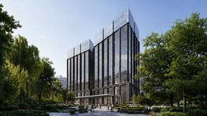 Un edificio moderno con fachada de vidrio, rodeado de árboles y un jardín cuidado.