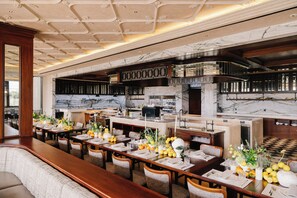 A spacious dining area with marble flooring, wooden tables, and chairs. - Marqen Hotel (Jakarta)