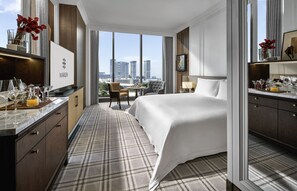 A hotel room with a bed, a desk with a minibar, a view of the cityscape, and a large window. - Marqen Hotel (Jakarta)