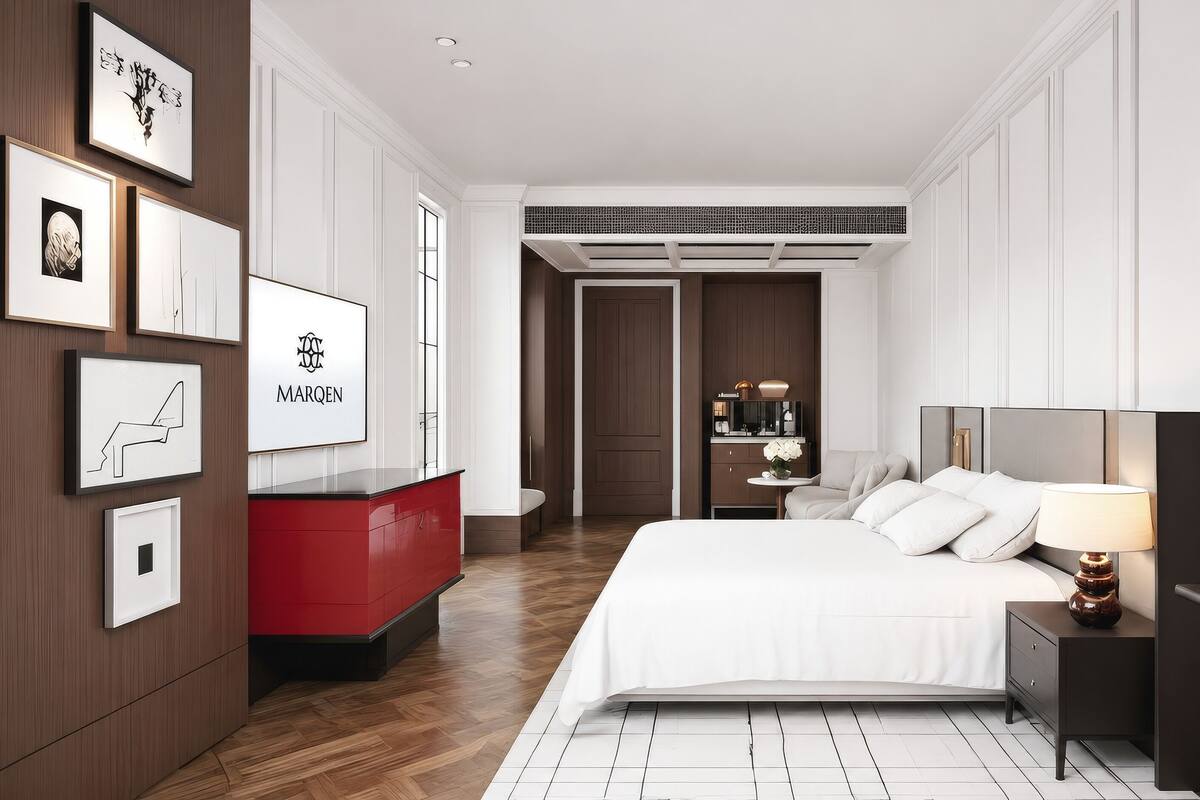 A modern hotel room with a bed, bedside table, nightstand, and a red dresser.