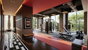 Un gimnasio moderno con equipamiento de ejercicio, una banca y ventanas amplias que dan a zonas verdes.