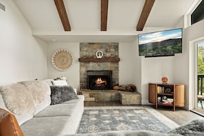 A living room with a stone fireplace, a mounted TV, and a bookshelf. - PREMIER 4BR LAKEFRONT HOME + BEST VIEWS + GENERATOR + EASY ACCESS TO LAKE (Crestline)