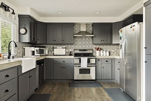 A modern kitchen with grey cabinets, stainless steel appliances, and patterned backsplash. - PREMIER 4BR LAKEFRONT HOME + BEST VIEWS + GENERATOR + EASY ACCESS TO LAKE (Crestline)