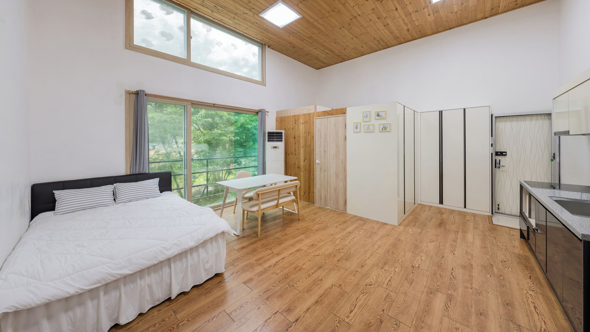 Un dormitorio con cama, una mesa y un armario.