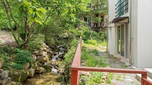 A serene garden with a small stream, a stone pathway, and a building with large windows.