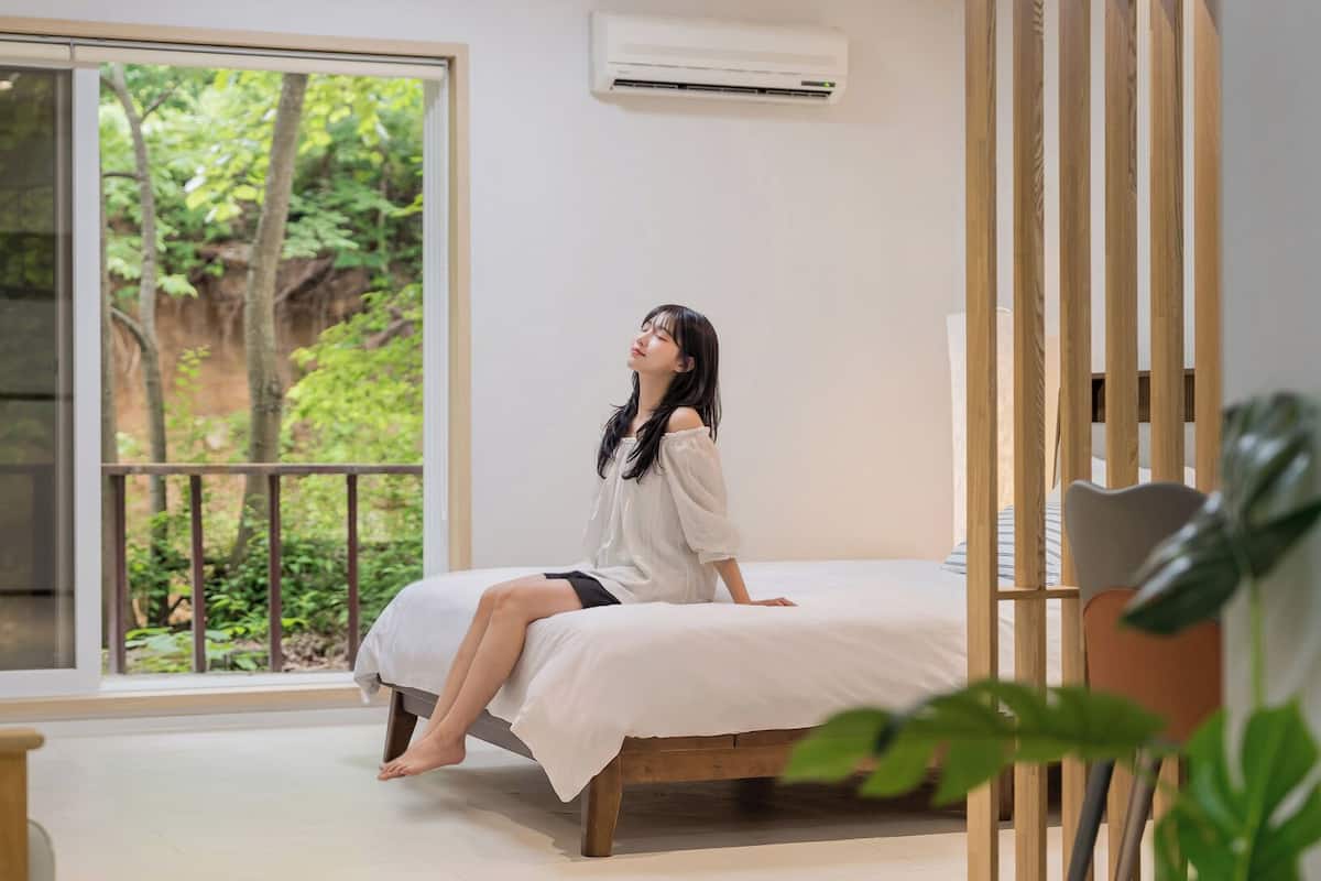 Una habitación con cama, ventana grande y vista a zonas verdes.