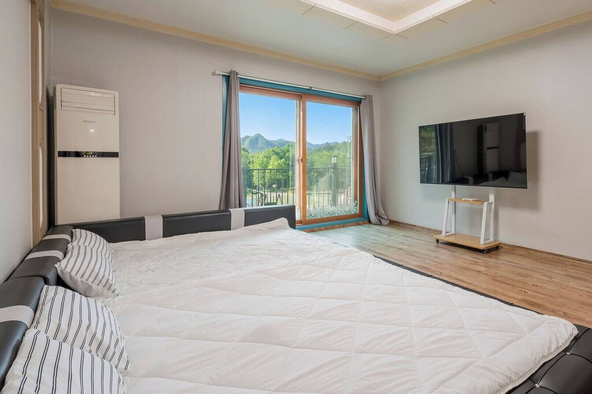 Un dormitorio con una cama grande, televisión, armario y puerta corredera de cristal a un balcón.
