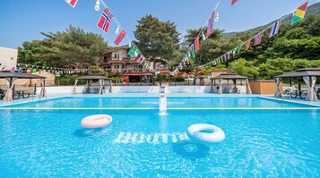 A swimming pool with flags, lounge chairs, and a building in the background.