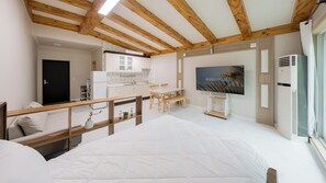 Un dormitorio con cama, televisor, kitchenette y zona de comedor.