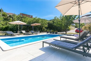 A swimming pool with lounge chairs and umbrellas, surrounded by greenery and buildings. - Two bedroom apartment with a swimming pool Marina, Trogir (A-27449-b) (Marina)