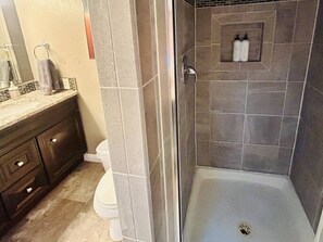 A bathroom with a shower, toilet, and vanity.