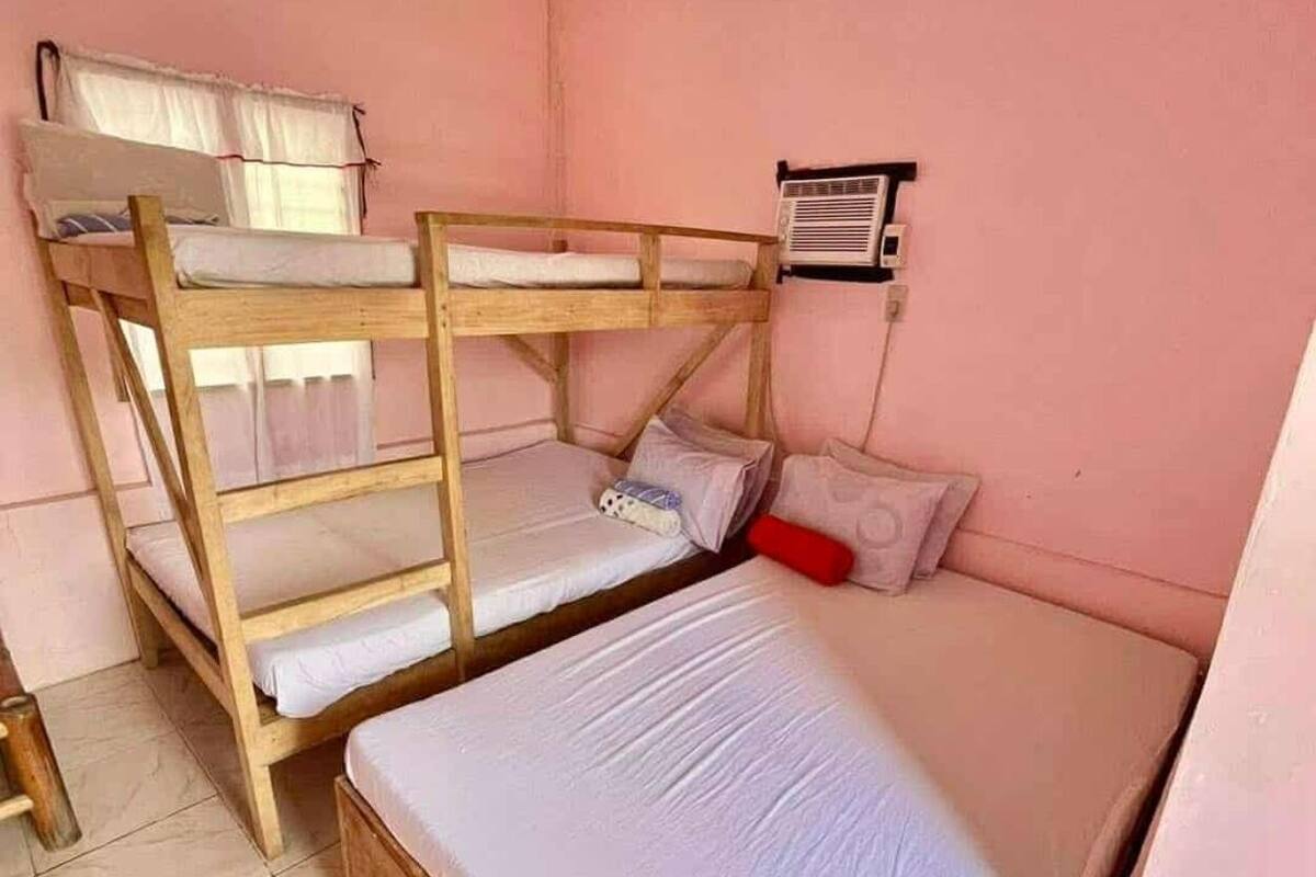A bunk bed room with a window, an air conditioning unit, and a red pillow.