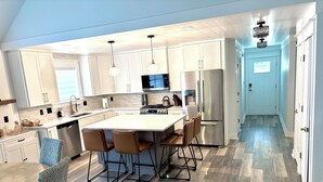 A modern kitchen with a central island, stainless steel appliances, and a dining area with chairs. - Spacious Lake Lanier property - Close to Atlanta and full of amenities (Buford)