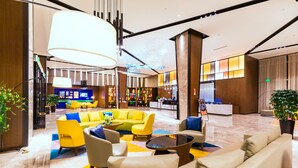 A modern hotel lobby with a reception desk, seating area, and a bar/lounge. - Hampton by Hillton Xiamen City Plaze (Xiamen)