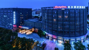 A modern hotel with a prominent circular building and a flat-roofed structure. - Hampton by Hillton Xiamen City Plaze (Xiamen)